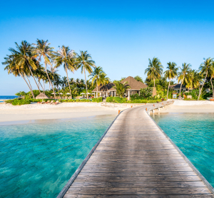 Holzsteg f&uuml;hrt &uuml;ber t&uuml;rkisfarbenes Wasser zu einer tropischen Insel mit Palmen und Bungalows auf Fidschi.