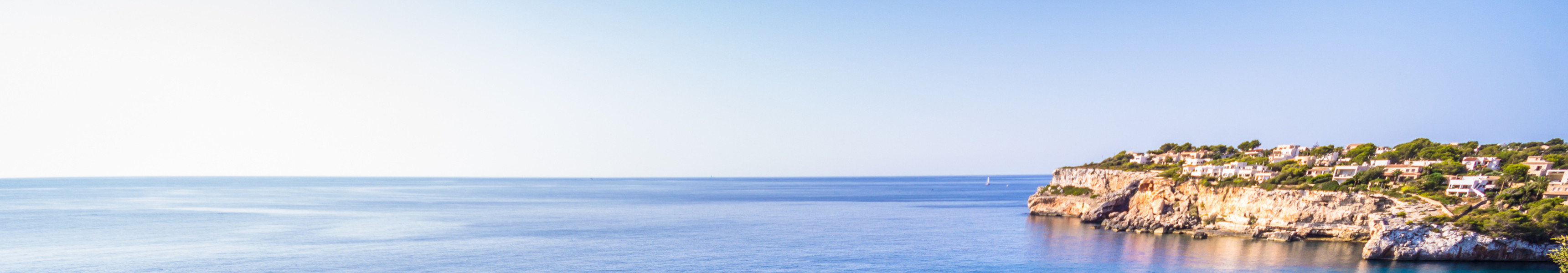 Nat&uuml;rlicher Felsbogen Es Pont&agrave;s im t&uuml;rkisblauen Mittelmeer vor der K&uuml;ste Mallorcas, umgeben von Klippen und gr&uuml;ner Vegetation.