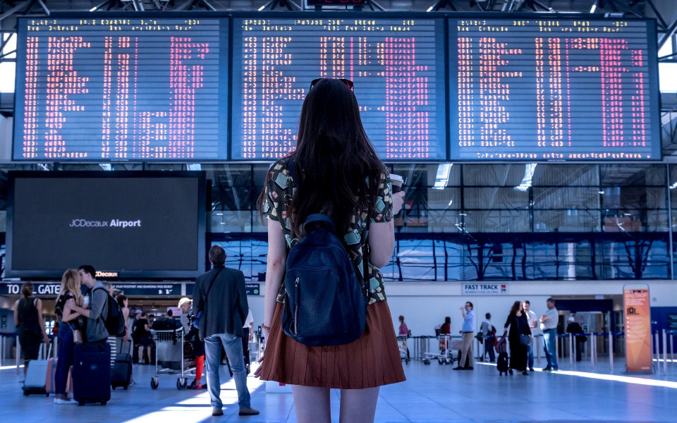 Frau am Flughafen &uuml;berpr&uuml;ft Abflugzeiten