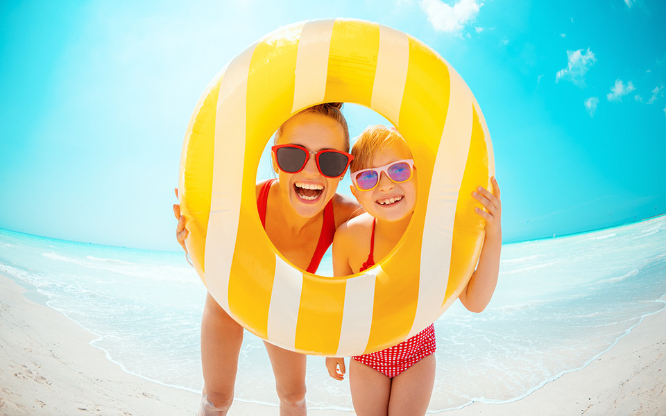 Frau und Kind sehen durch einen Schwimmreifen am Strand