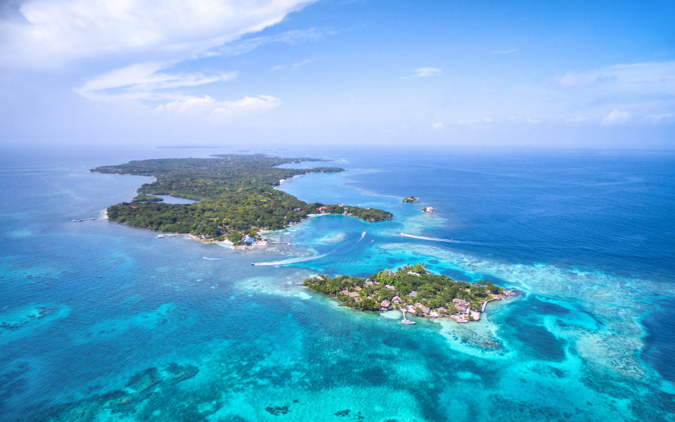 Koralleninselgruppe vor der Karibikküste Kolumbiens mit türkisfarbenem Wasser und dichter Vegetation.