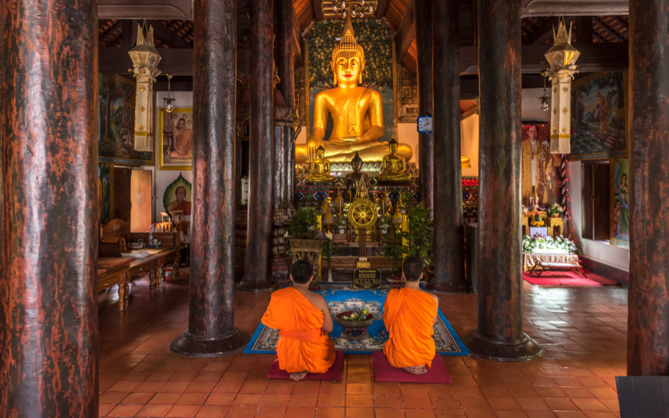 Buddhistische M&ouml;nche sitzen zu religi&ouml;sen Zeremonien vor der Buddha-Statue im Tempel.